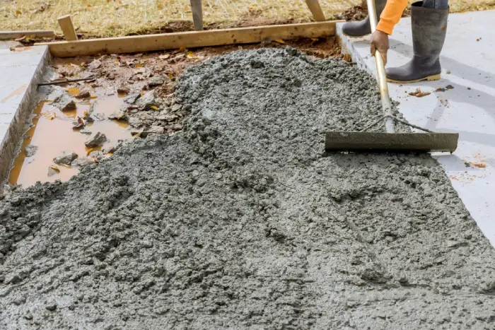 Worker smoothing wet concrete with a trowel on a construction site